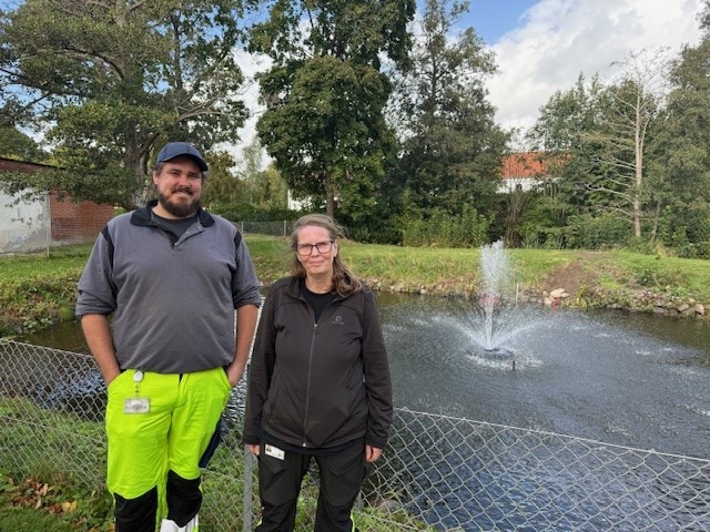 Foto af Filadelfias gartnere Torben Granlyn og Susanne Camin. De står ved en sø med springvand.