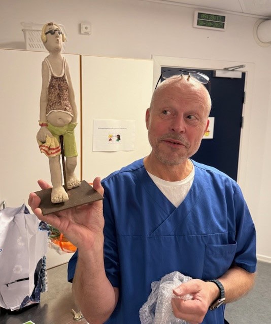 Udviklingssygeplejerske Klaus Ehrenreich fejrer 40-års jubilæum og står med en keramikfigur, han har fået i gave.
