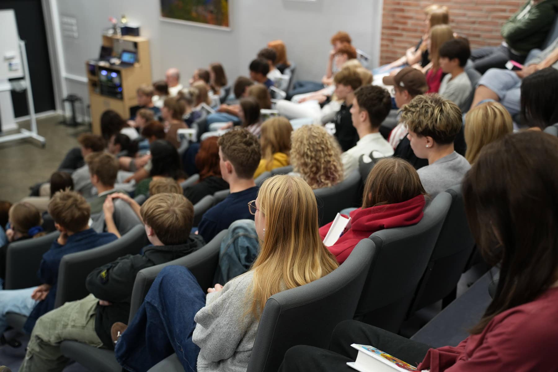 Elever på efterskole lytter, mens de sidder på stolerækker